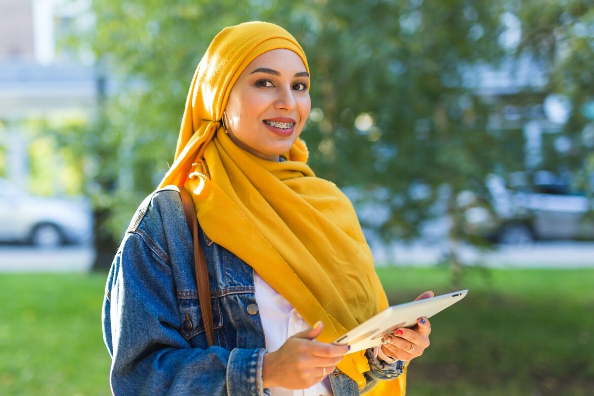 Arab woman student. Beautiful muslim female student wearing bright yellow hijab holding tablet Arab woman student. Beautiful muslim female student wearing bright yellow hijab holding tablet