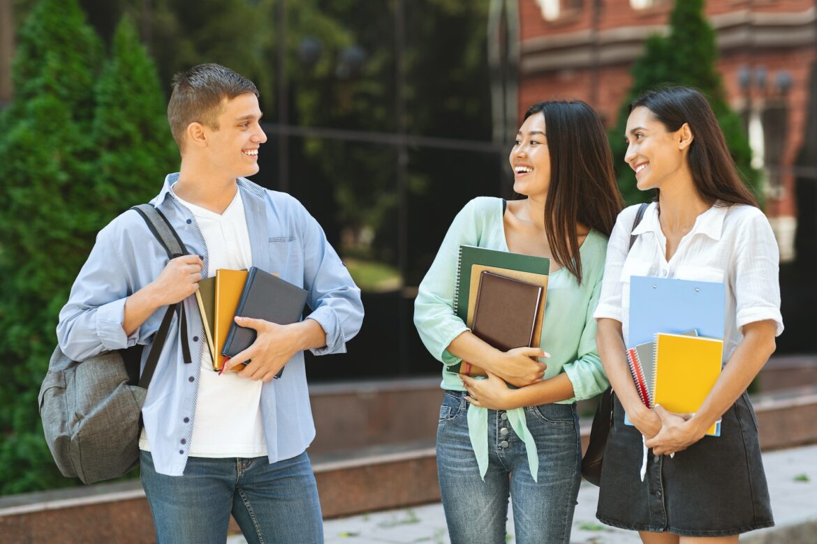 Handsome University Student Chatting With Two Female Classmates Outdoors Handsome University Student Chatting With Two Female Classmates Outdoors