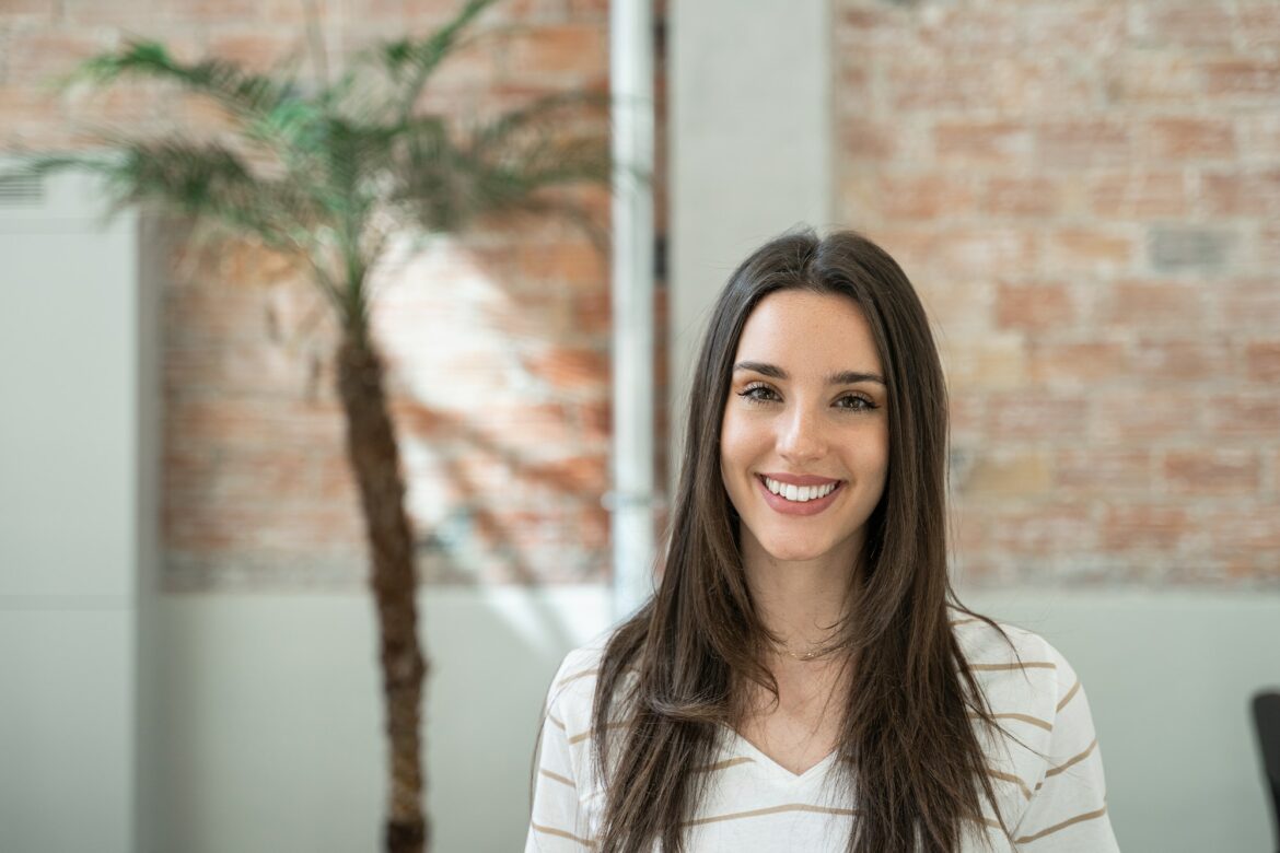 Young woman creative professional employee in a modern office with brick walls doing internship