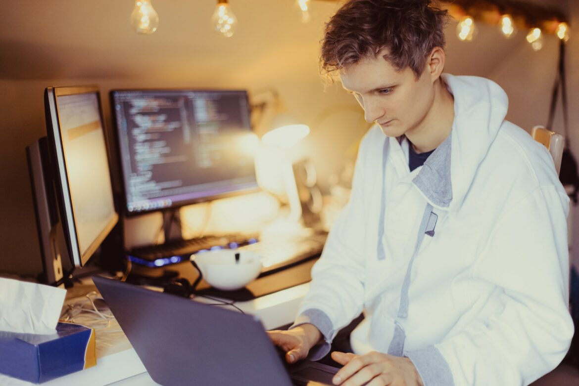 IT specialist programmer writing code on his pc and laptop. Developer remote home office. Freelance IT specialist programmer writing code on his pc and laptop. Developer remote home office. Freelance